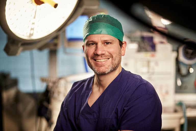 Portrait photograph of Dr William Blakeney in surgical scrubs and cap.
